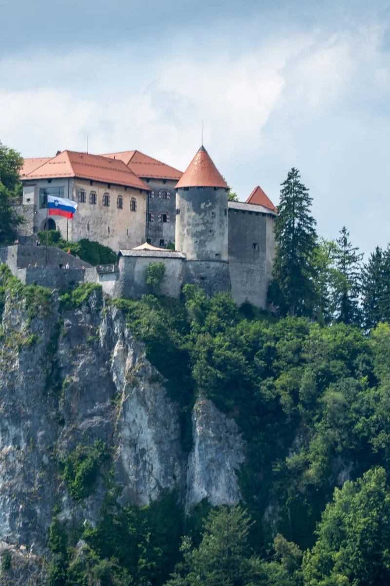 Bled Castle on its cliff above the emerald water of Lake Bled, with the island church and the Julian Alps behind